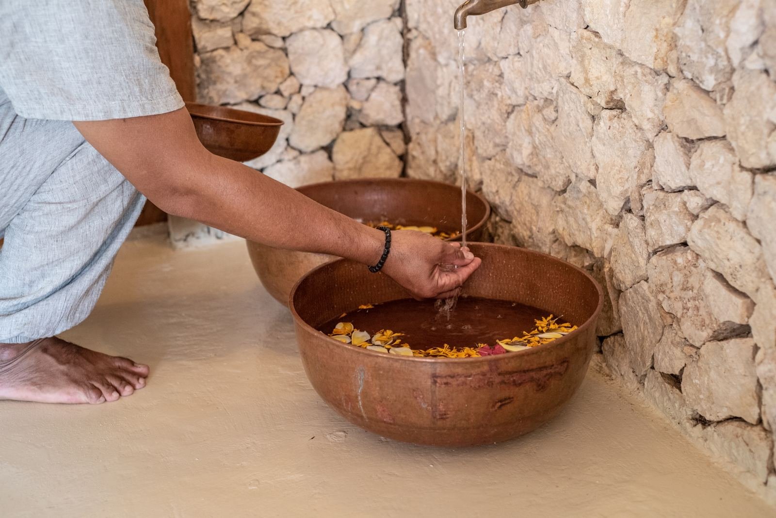 Water poured into a copper bowl with flowers