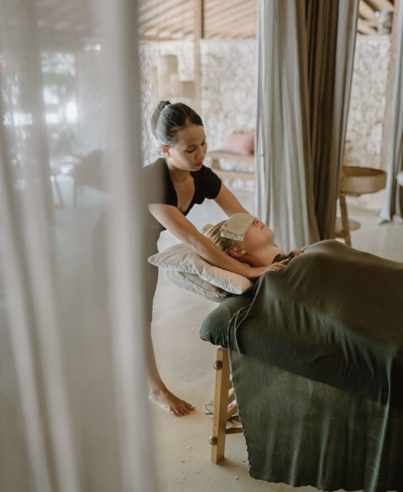 A shi•ra therapist giving a massage, the guest resting with an eye pillow